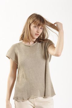 a woman is standing with her hair in the air and looking at the camera while wearing a tan sweater