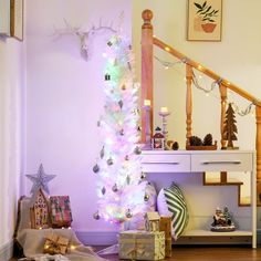 a white christmas tree is lit up in the corner of a room with other decorations