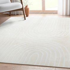 a large white rug with wavy lines on the floor in front of a chair and window