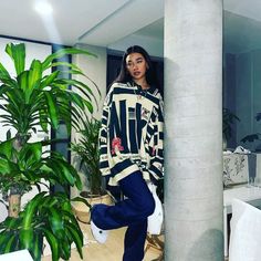 a woman is standing in the middle of a room with plants and potted plants