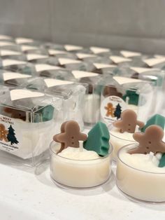 four small candles are sitting on a table with christmas decorations in the glass containers behind them