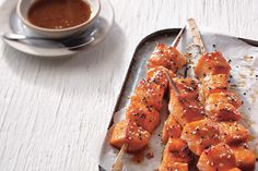 several skewers of food on a tray with dipping sauce