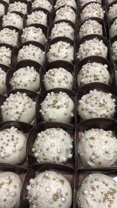 several trays filled with white and gold decorated desserts on top of each other