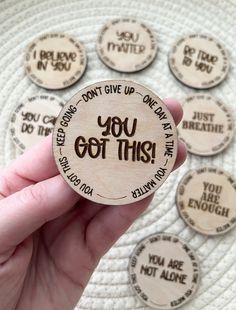 a person holding up a wooden badge with the words you got this written on it