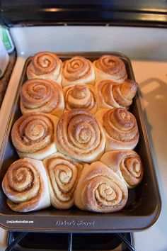 a pan filled with cinnamon rolls sitting on top of a stove