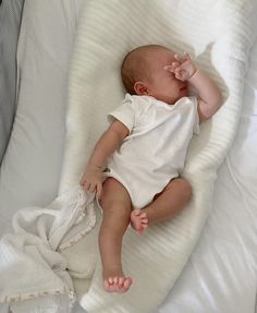 a baby laying on top of a white blanket