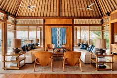 a living room filled with lots of furniture and wooden flooring next to tall windows