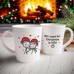 two coffee mugs sitting next to each other on a table in front of a fireplace