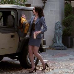 a woman standing next to a car with a jacket hanging out of it's door