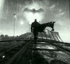 a man walking down train tracks in the rain with a bat on his back and an umbrella over his head