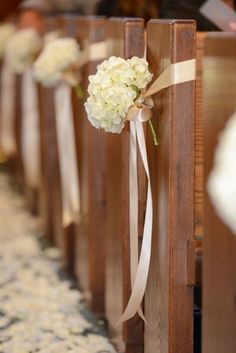 white flowers tied to wooden pews at a wedding