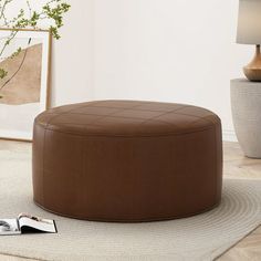 a brown leather ottoman sitting on top of a rug next to a vase and lamp