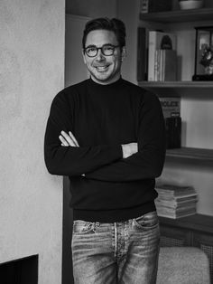 a black and white photo of a man with his arms crossed, leaning against a wall