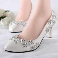 the woman is wearing white high heels with flowers on each side of her shoe,