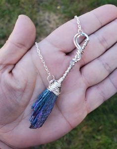 a hand holding a tiny blue tassel on a silver plated chain with an open loop