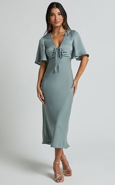 Get ready to turn heads in the Nicholla Midi Dress! This stunning A-line dress features a ruched front and angel sleeves that add an ethereal touch. Made from luxurious satin polyester, this dress has a V-neckline and falls perfectly at midi length for a flattering silhouette. Whether you're attending a cocktail party or a wedding as a guest, the sage green color of this dress will make you stand out from the crowd. With its short sleeves and comfortable fit, the Nicholla Midi Dress is both styl Satin Midi Dress With Sleeves, Slip Dress With Sleeves, Wedding Guest Dress Sleeves, Midi Bridesmaid Dress, True Summer, Basic Black Dress, Dress Code Wedding, Sage Green Color, Bachelorette Dress