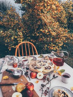 an outdoor table with apples, pies and other food on it in the fall