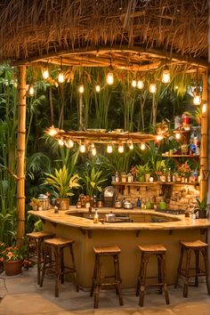 an outdoor bar with stools and lights hanging from it's ceiling, surrounded by greenery