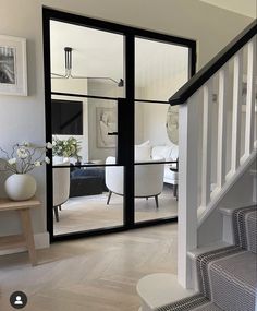 an open door leading to a living room with white furniture and black framed glass doors