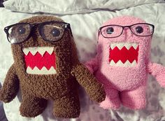 two stuffed animals wearing glasses on a bed