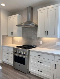 a stove top oven sitting inside of a kitchen next to white cupboards and drawers