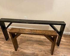 a wooden bench sitting on top of a hard wood floor next to a white wall