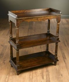 an old wooden shelf with three shelves on it's sides, sitting on a hard wood floor