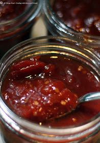 several jars filled with different kinds of food and one has a spoon in the jar