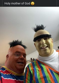 two men with fake hair are standing next to each other, one is wearing a striped shirt and the other has black mohawks on his head