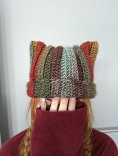 a woman wearing a knitted cat hat covering her face