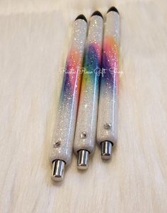 three different colored pens sitting on top of a table