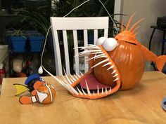 an orange fish sitting on top of a wooden table next to a toy clownfish