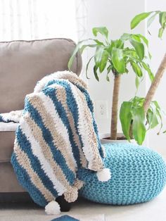 a blue and white blanket sitting on top of a couch next to a potted plant