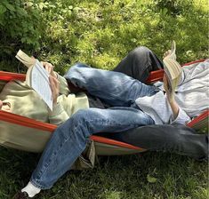 two people laying in a hammock reading books