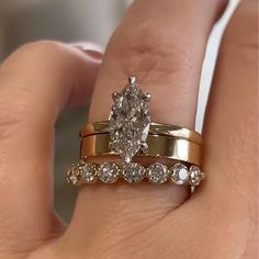 a woman's hand with two gold wedding rings and an engagement ring on her finger