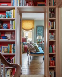 a living room filled with lots of books on top of a wooden floor next to a doorway