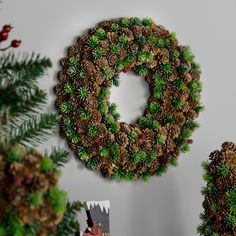 a christmas wreath made out of pine cones hanging on the wall next to other decorations