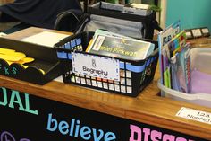 there is a desk with some books and other items on it, including a basket