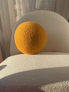 an orange ball sitting on top of a white chair