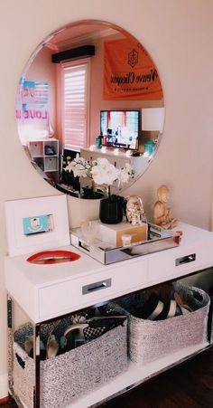 there is a mirror on the wall above a desk with drawers and baskets in front of it