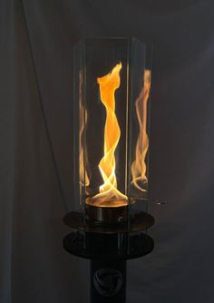 a light that is glowing on top of a glass table with flames coming out of it