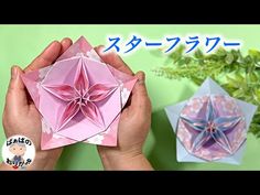 two origami flowers are shown in front of each other, one is pink and the other is blue