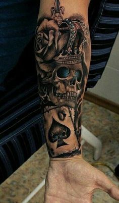 a man's arm with a skull and roses tattoo on the left hand, holding a playing card in his other hand