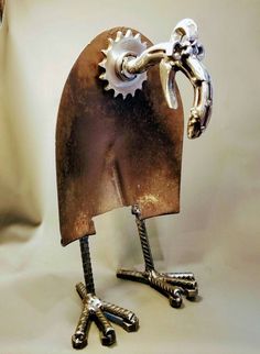 a metal sculpture of a bird with gears on its body and feet, holding a wrench