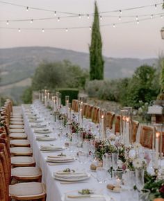 a long table is set up with place settings and candles for an outdoor dinner party