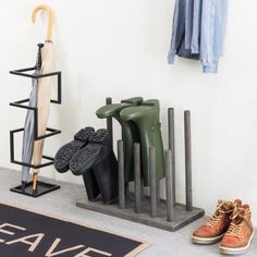 several pairs of shoes and umbrellas are on the floor next to a coat rack