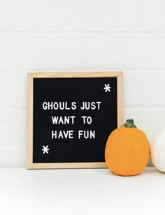 two pumpkins sitting next to a sign that says ghouls just want to have fun