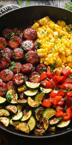 a skillet filled with vegetables and corn on the cob next to other foods