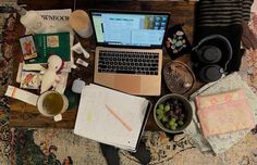 an open laptop computer sitting on top of a wooden table next to other items and utensils