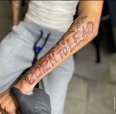 a man is holding his arm with the word born to lead on it in red ink